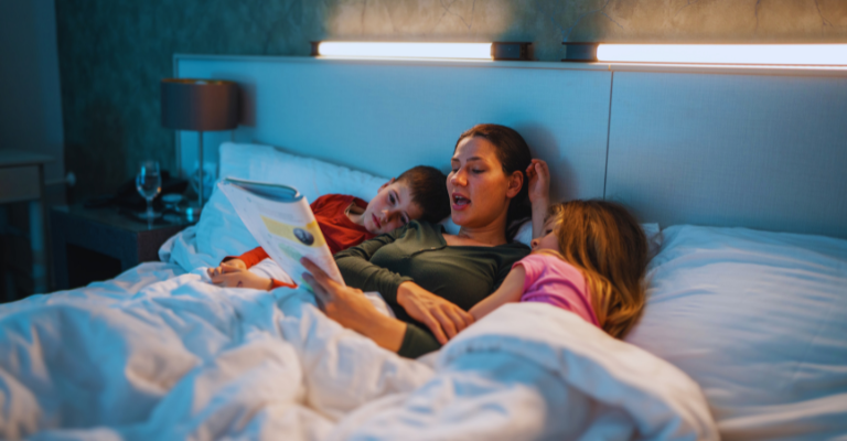 žena číta deťom v posteli knihu